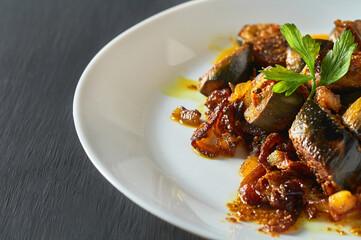 Served dish of fried bananas with onion and curry in restaurant on concrete table