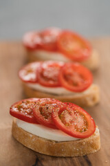 Simple bruschetta with tomatoes and mozzarella on olive wood board