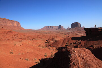 A woman riding on Horse  from John Ford's Point overlook in Monument Valley Tribal Park with the mittens and Merrick Butte in Arizona, USA