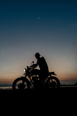 Fototapeta na wymiar Male model on a custom bike during sunset in the beach