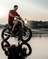 Male model on a custom bike during sunset in the beach