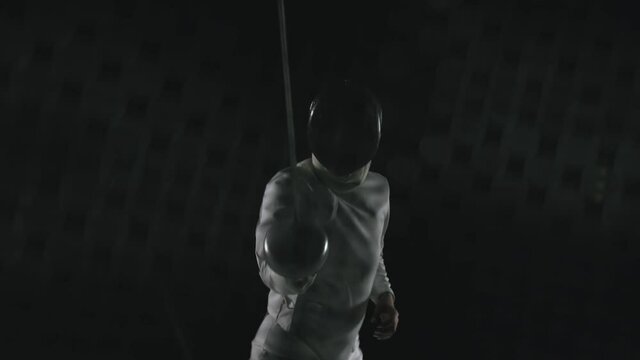 Duel, battle of two fencing athletes . Shot of the camera from inside the fencing mask. Black background. Slow motion. Close up.