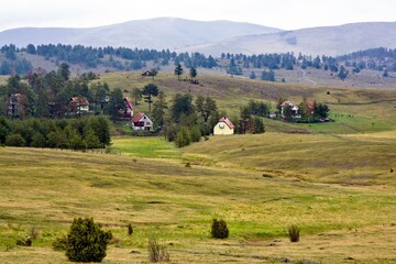 Small houses surrounded with hills and green trees in Zlatibor, Serbia.