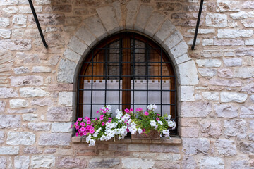 Fototapeta na wymiar Typical Italian Window With Closed Wooden Shutters, Decorated With Fresh Flowers