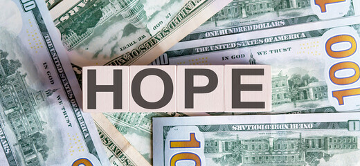 Fototapeta na wymiar Concept words HOPE on wooden blocks on a beautiful background from dollar bills.