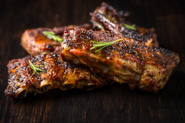 Grilled pork spare ribs with rosemary on wooden background.