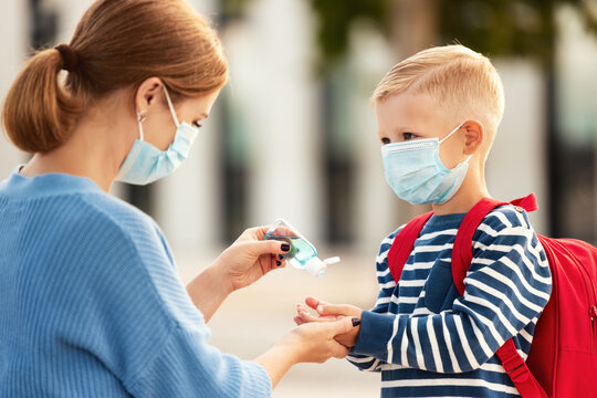 Concept of preventing a coronavirus covid-19 and viral infections. Mother treats her child's hands with a sanitizer before school.