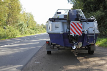 Motor boat on Car trailer back view on transom stern with powerful 100 hp outboard motor on freeway...