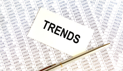 Obraz premium The inscription on the TRENDS business card, next to the report and the pen.