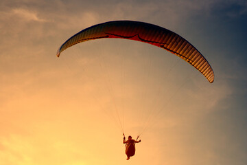 Paraglider flying on the res sky in sunset time in summer day. Cloud clear background.