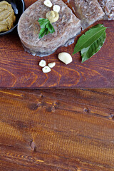  Home jelly, cut into portions lying on the kitchen Board.Near mustard, garlic, Bay leaf, parsley. Copy space. Top view.