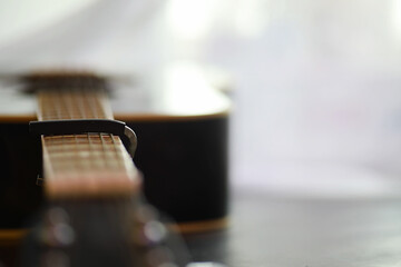 An acoustic guitar for an artist playing a stringed musical instrument on stage. Black guitar with a capo. Musical background.
