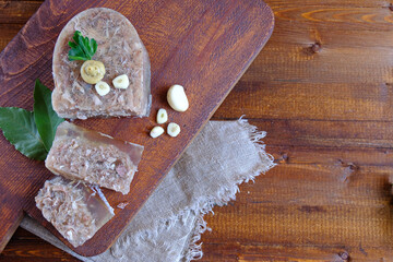  Home jelly, cut into portions lying on the kitchen Board.Near mustard, garlic, Bay leaf, parsley. Copy space. Flat lay.