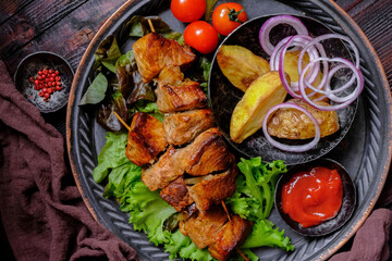 Skewers of Meat with sauce on wooden cutting board, ready to be served as summer party meal, view from above.