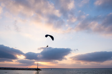 Motorized paraglider in amazing sunset sky above Ashkelon`s Marina