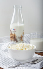 Homemade crumbly cottage cheese on a wooden background. Cottage cheese with a bottle of milk and a glass on a wooden background.
