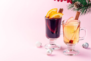 Red and white glogg or mulled wine with orange and apple slices and cinnamon stick, Christmas decoration pink background, horizontal, copy space