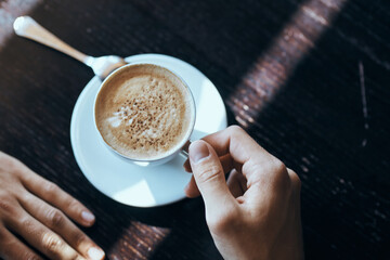 Cup of coffee on the table with white rice and a teaspoon of cafe mens hands.