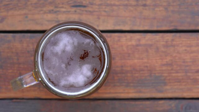 Man takes glass of fresh beer from wooden table outdoors