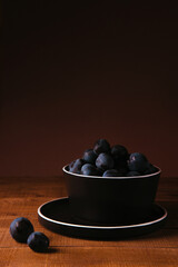 Still life, black plums in the composition, dark photo.