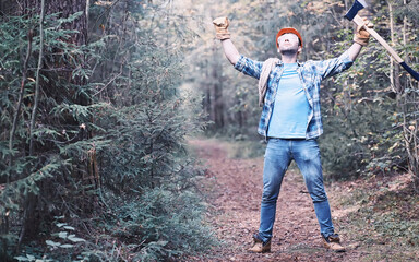 Male lumberjack in the forest. A professional woodcutter inspects trees for felling.
