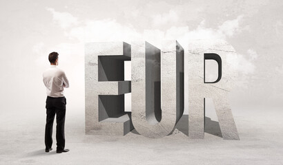 Fototapeta premium Rear view of a businessman standing in front of EUR abbreviation, attention making concept