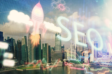 SEO hologram on city view with skyscrapers background double exposure. Search optimization concept.