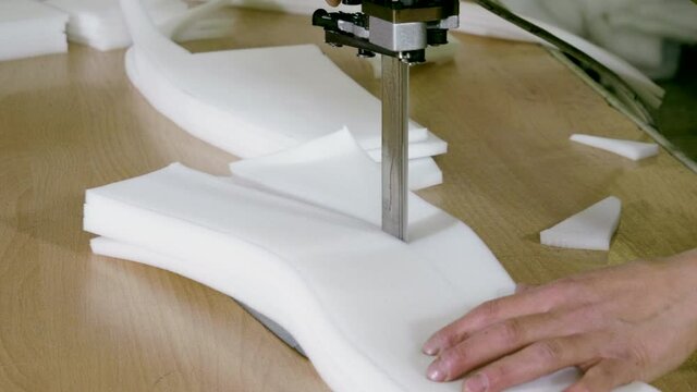 An female worker cutting foam rubber for the production of a sofa in a furniture factory. 4K