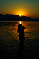 silhouette of a girl on the background of sea mountains and sunset