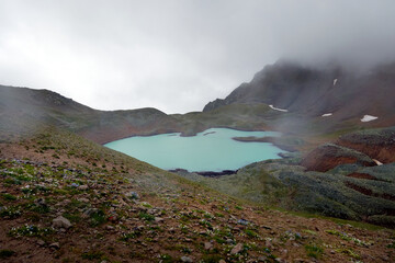 Alpine lake in the clouds. Alpine lake Giybashkel (3240 meters above sea level), Pastushiy pass (3244 meters above sea level), Caucasus.