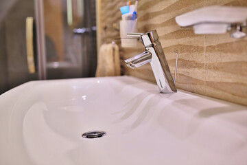 Luxury faucet mixer on a white sink in a beautiful gray interior bathroom. close up view of nice...