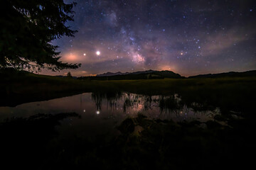 A starry night with thee Milky Way partly reflecting in a little pond at the so called Winklmoosalm...