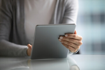 Close up businesswoman holding computer tablet, browsing apps, searching information in internet, young woman writing student employee message, chatting in social network or shopping online