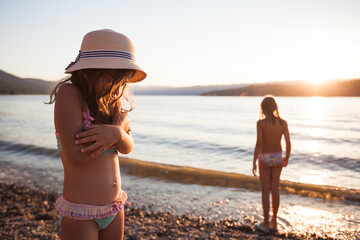 Fototapeta premium Children on the beach at sunset, beautiful summer sunlight reflection at water