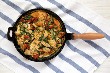 Homemade Creamy Tuscan Chicken in a cast-iron pan, overhead view. Flat lay, top view, from above.