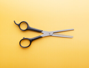 Thinning scissors isolated. Professional hairdressing shears on yellow background