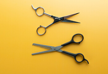 Scissors for haircut and thinning hair on yellow background, open and close up