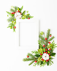 Christmas composition  with photo frame, cotton flower, branches of spruce and holly with red berries on white background. Merry christmas greeting card with empty space for holiday text.