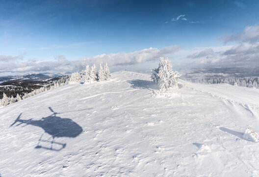 Landing helicopter shadow on a snow covered mountain.