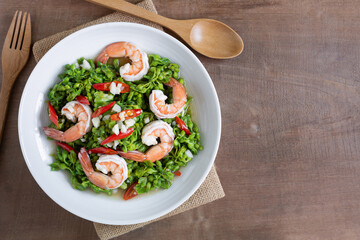 top view of stir fried cowslip creeper with shrimps in a ceramic dish on wooden table. homemade...