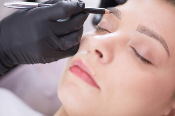 Cosmetologist applying permanent make up on eyebrows