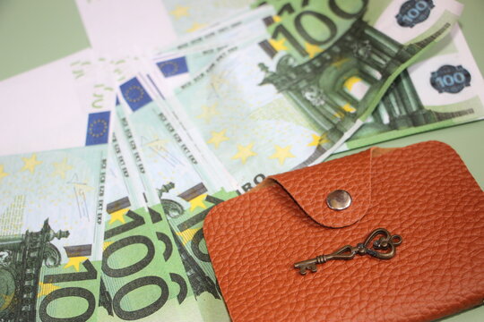 Many 100 Euro bills, brown leather wallet and vintage key. Business concept