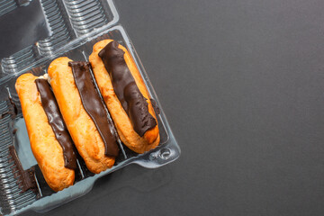 Eclairs with cream filling drenched in chocolate on a black the background
