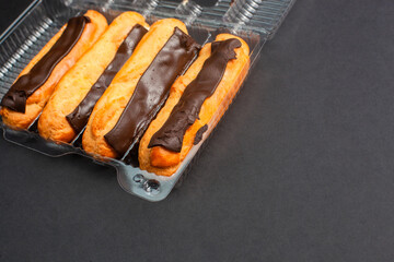 Eclairs with cream filling drenched in chocolate on a black the background