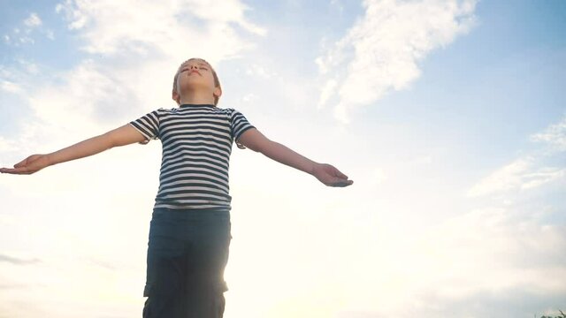 boy prays pulls hands to the sky against a blue sky. child lifestyle concept faith religion and happy family. kid son hands to the side against the blue sky jew praying to god. worship and gratitude