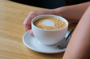 a cup of cappuccino coffee in hand