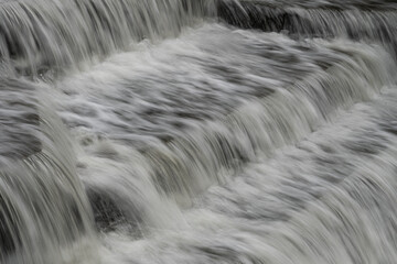 White Water flowing over weir low-level view at long exposure for blurred water effects and textures 