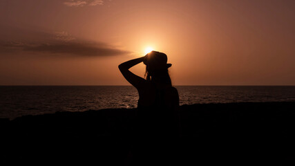 Silhouette of a woman with hat during sunset