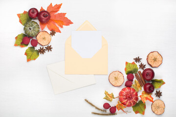 Autumn floral composition with pumpkins and empty blank card in paper envelope.