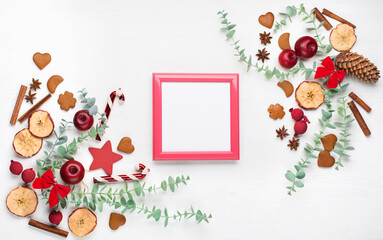 Red empty frame, pine cones, fir tree branches, red berries on white table background.